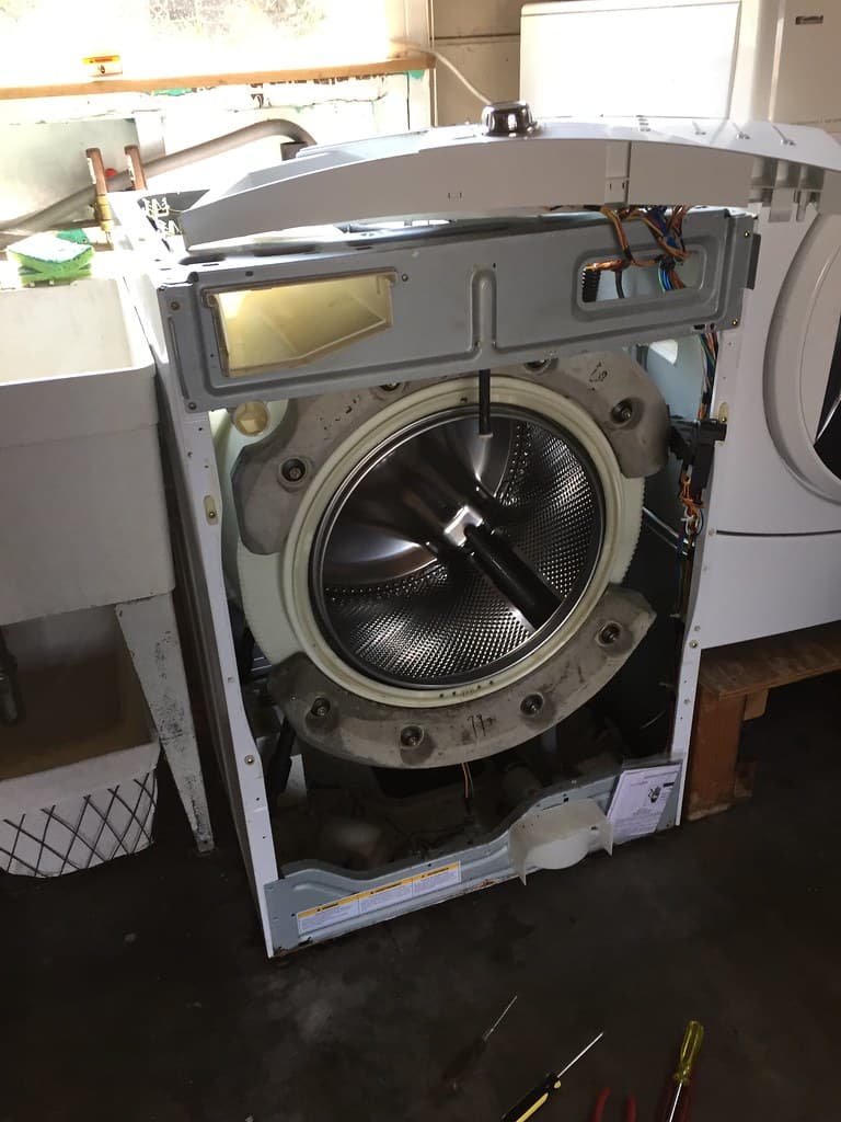 Technician repairing a washing machine at home
